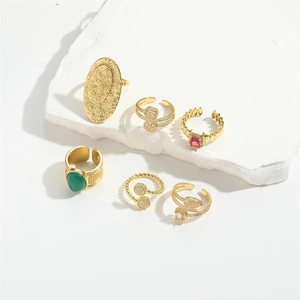 Detail shot of vintage gold open rings with green and red gemstones on a stone base