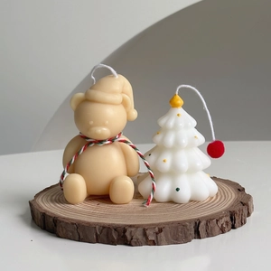 Detail of mini Christmas candles featuring a bear and tree on a rustic wooden base