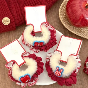 Close-up of red plush hair scrunchies with cute animal charms and lace details in a ceramic dish