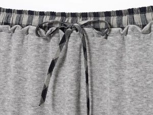Detail of grey knit fabric with contrast plaid waistband and drawstring tie design
