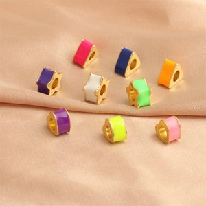 Close-up of colorful enamel heart and star beads on beige silk for DIY jewelry making