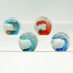 Detail of four colorful glass wave spheres with internal bubbles on a white display stand