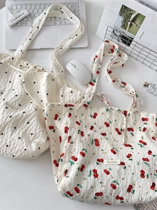 Floral and cherry print seersucker tote bags shown on a desk with a laptop