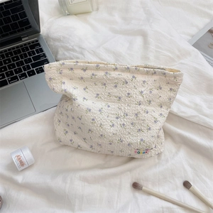 Detail of floral quilted makeup bag with soft texture, luxury creams and laptop background
