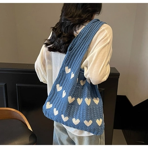 Detalle del tejido de punto y corazones blancos en el bolso de hombro azul