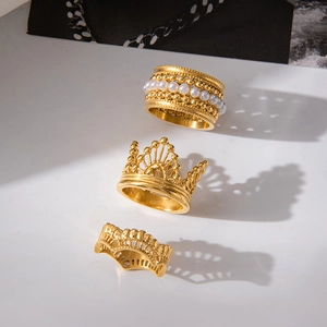 Detailed view of three gold-plated stainless steel rings with pearls and lace crown patterns