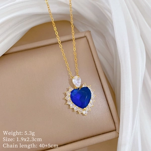 Detail of gold heart necklace with blue gemstone and diamonds on a jewelry box