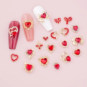 Macro shot of red heart nail charms with gold bases and pearls for DIY nail art