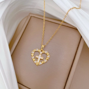 Detail of gold heart pendant with crystal border and mother of pearl cross on silk