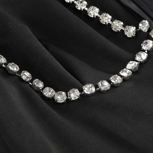 Detailed close-up of sparkling silver rhinestone trim on black V-neck evening party dress