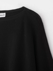 Detail of a black knit sweater featuring a round neckline and fine ribbed texture
