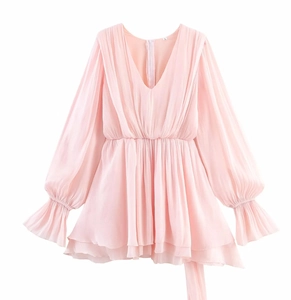 Detail of light pink chiffon V-neck dress featuring ruffled cuffs and layered hemline