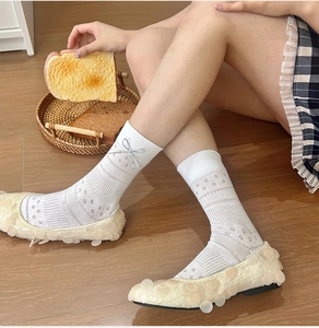 Detail weißer Ballettsocken mit Rautenmuster und dekorativen silbernen Schleifen