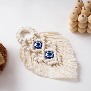 Close-up of bohemian leaf-shaped macrame wall hanging with blue evil eye beads