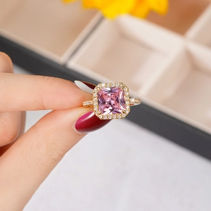 Close-up of a gold ring with a large square pink gemstone and sparkling clear accents