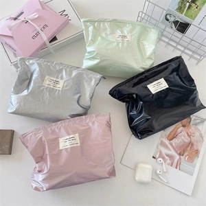 Flat lay of glossy storage bags in silver, green, black and pink with stylish accessories