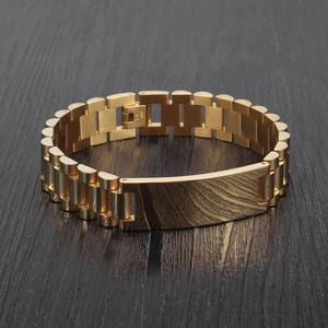 Detail view of 15mm gold watch-strap style men's wide bracelet on dark wood background