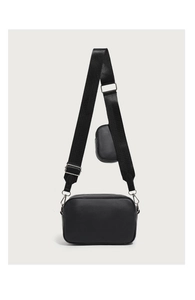 Close-up of black quilted camera bag with wide strap and attached coin purse detail