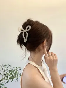 Elegant cream bow hair claw clip shown from back view on model's hair style