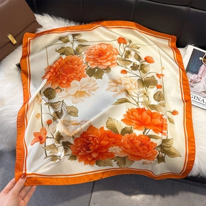Détail d'un foulard élégant en soie à imprimé floral avec contrastes orange et beige