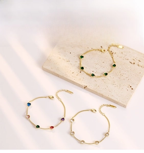 Detail view of dainty gold bracelets with colorful heart-shaped cubic zirconia stones