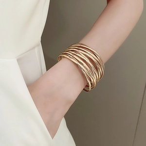 Detailed view of multilayer stacked gold metal bangles in a minimalist open design