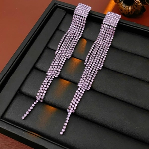 Gros plan de longues boucles d'oreilles pampilles en argent avec strass roses sur cuir noir