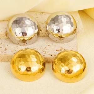 Gros plan de boucles d'oreilles rondes martelées en or et argent sur fond élégant