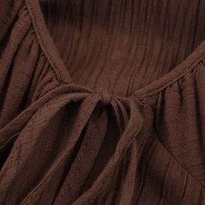 Macro detail of dark brown pleated fabric texture and drawstring neckline of the dress