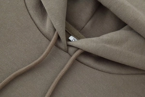 Detailed close-up of brown hooded sweatshirt neckline with woven drawstring and knit texture