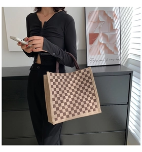 Brown checkered linen tote bag shown on shoulder in a warm lifestyle interior setting