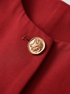 Macro shot of dark red twill fabric featuring a gold vintage textured metal button detail