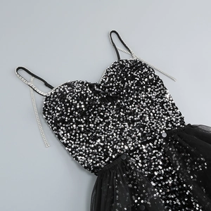 Detail of black sequined dress featuring rhinestone chain straps and sheer mesh fabric