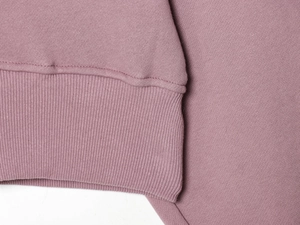 Gros plan des poignets côtelés roses et de la texture en coton tricoté du sweat à capuche