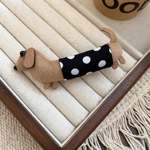 Detail of fabric dachshund hair clip with polka dot pattern on beige display tray