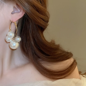 Détail rapproché de grandes créoles dorées avec perles élégantes portées par un mannequin