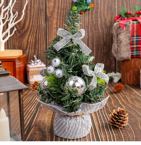Detailed view of mini Christmas tree with silver bows and ornaments on wooden desk