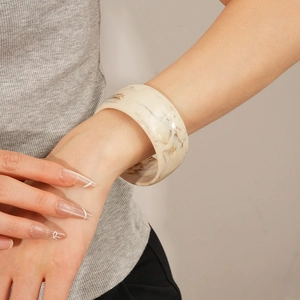 Close-up of a wide resin bangle with marble texture worn on a model wrist