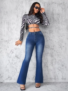 Détail de jean évasé taille haute avec crop top imprimé zèbre et sac à chaîne dorée