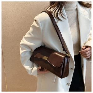 Detail einer dunkelbraunen Schultertasche aus Kunstleder mit eleganter Metallschnalle