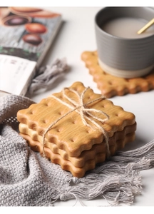 Detail of cookie-shaped solid walnut coasters stacked on a soft textured blanket