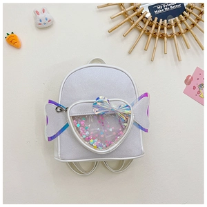Detail of white sequin backpack featuring rainbow wings and a heart-shaped transparent pocket