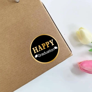 Macro detail of black and gold Happy Graduation stickers on a kraft gift box corner