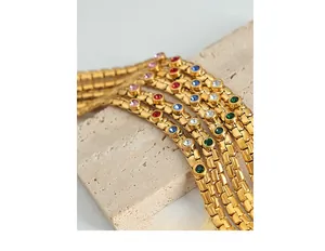 Macro detail of gold plated snake bone chains with multi-colored round zircon inlays