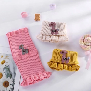 Flat lay of knit children's neck warmers in pink, beige, and yellow with ruffle trim