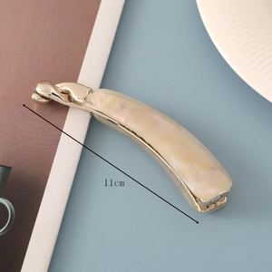 Detailed view of an 11cm acetate banana hair clip with pearlescent shell texture and gold base