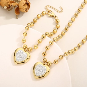 Detailed view of gold bead chain necklace and bracelet with sparkling heart pendants