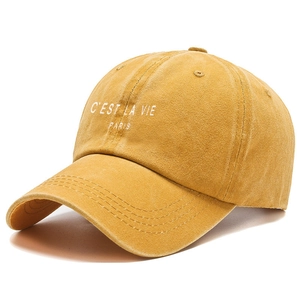 Detail of the white C'EST LA VIE PARIS embroidery on the vintage washed yellow cotton cap