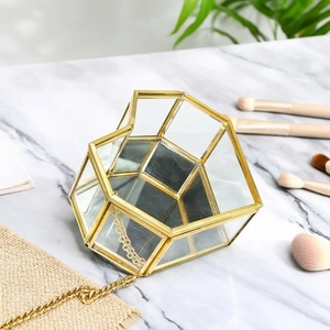 Macro shot of geometric glass jewelry box with gold metal frame on marble surface