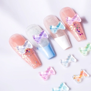 3D aurora resin bow nail charms in various colors on shimmering gradient manicures